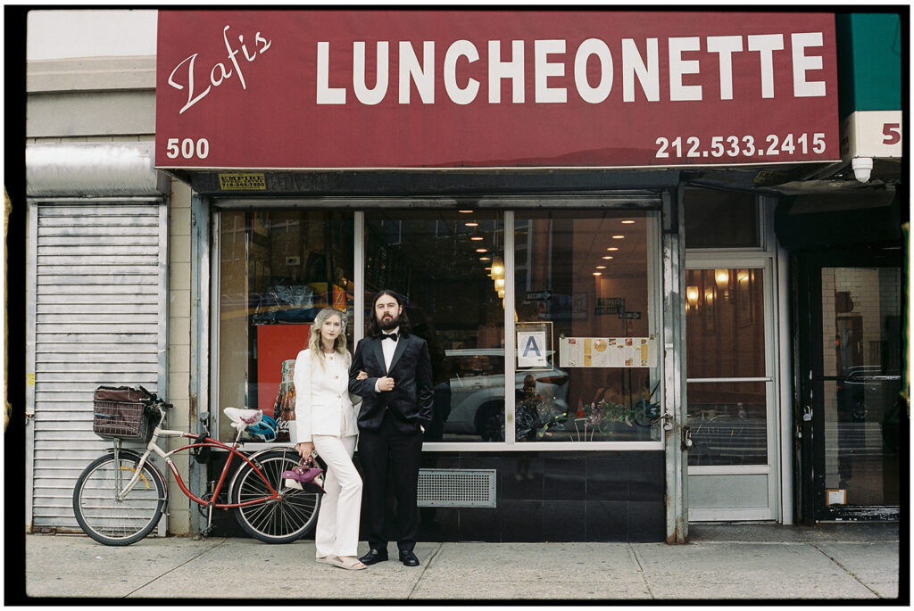 NYC elopement photographer captures bride and groom in diner sharing pancakes for their wedding dinner, candid film photography.