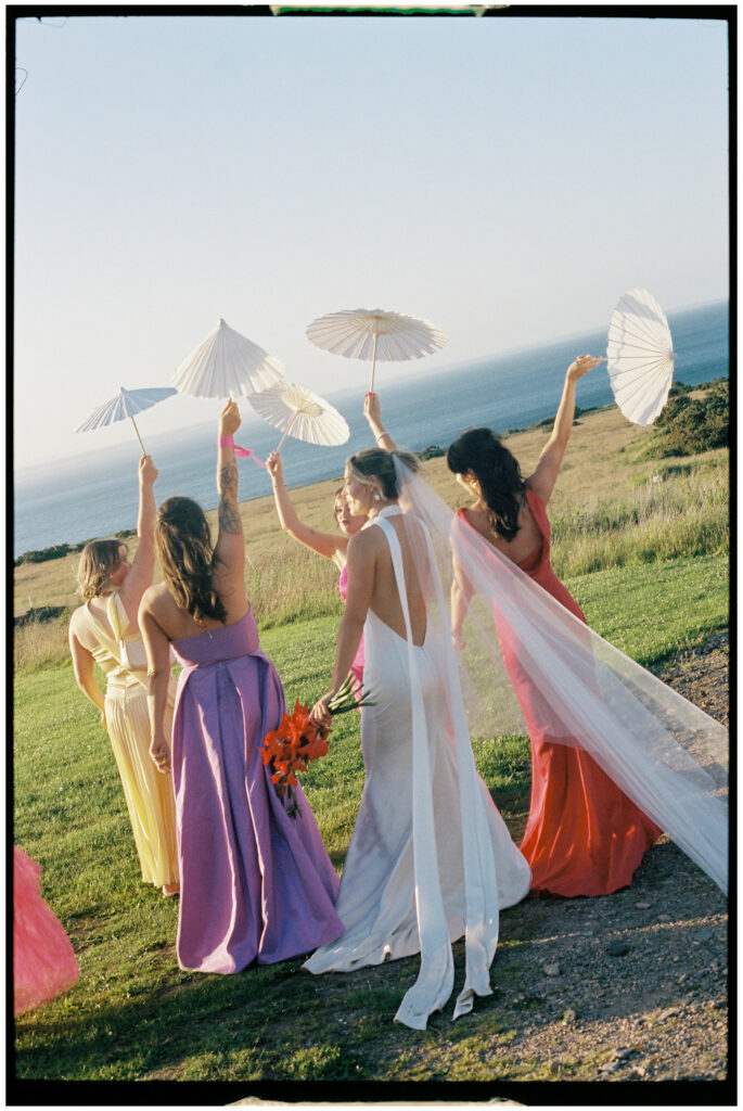 Bride and bridesmaids in colourful dresses posing by vintage car, Kinkell Byre wedding shot on film