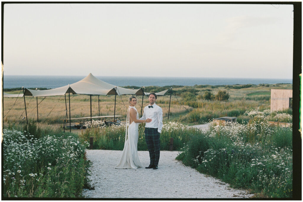 Bride and groom leaning on white classic car with sea view, film wedding photographer Scotland